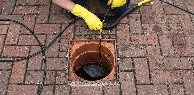 Drain cleaning technician using a drain snake to clear a clogged drain in Mesa, AZ