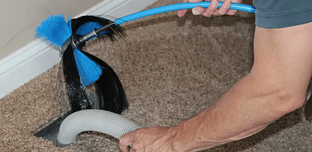 Dryer vent cleaning technician brushing lint from a vent line in Mesa, AZ