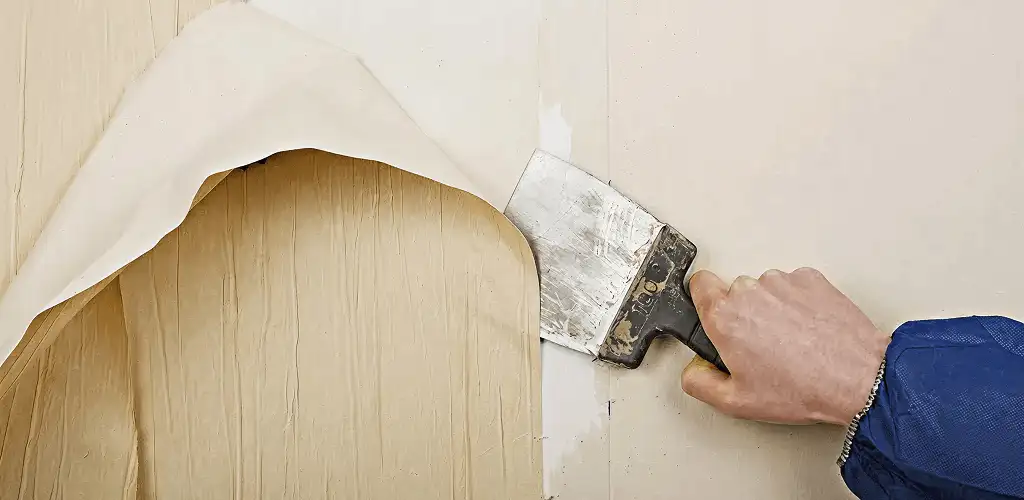 Handyman removing wallpaper with a scraper for wall preparation in Mesa, AZ