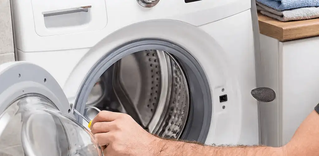Handyman repairing a front-load washing machine and inspecting the drum in Mesa, AZ