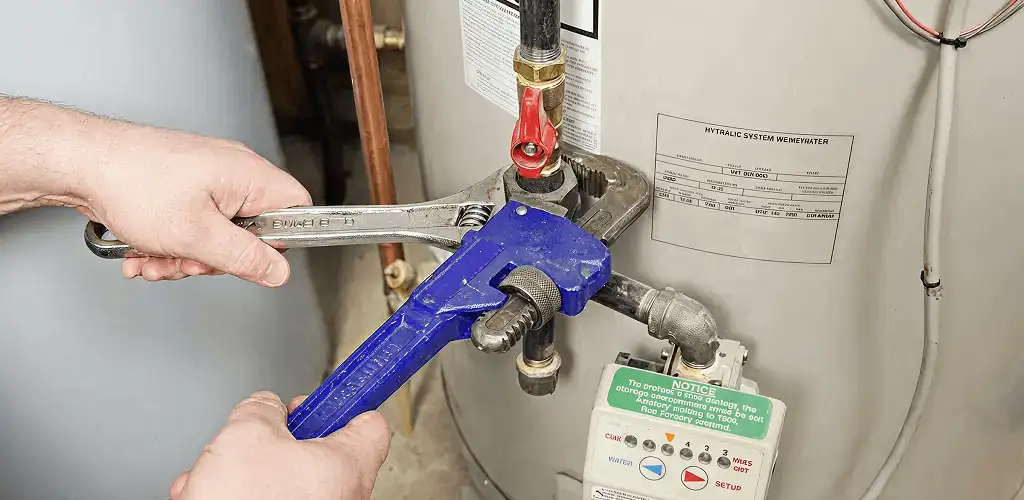 Water heater repair technician tightening the shutoff valve and supply line in Mesa, AZ